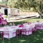 Barbie 6th birthday party with pink tables, ghost chairs, balloons and life-size doll box