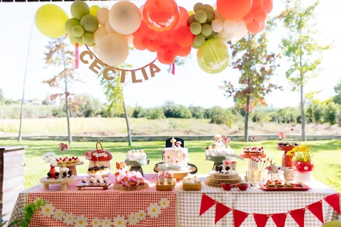 Cecília's finished picnic first birthday dessert table with balloon garland, cake, cupcakes and woodland decor