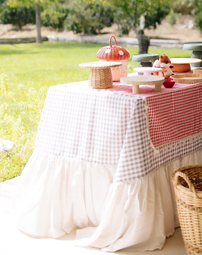 Layered ruffled gingham tablecloth beside a woven picnic basket