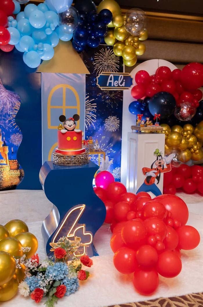 Minnie Mouse cake display with red gold navy and blue balloon decorations