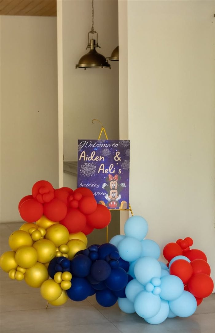 Tall royal Mickey and Minnie birthday cake framed by gold balloons