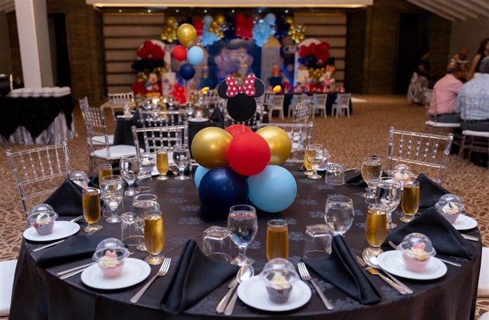 Elegant royal birthday table setting with black linens gold accents and balloons