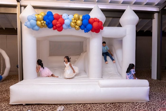 White castle bounce house decorated with red blue and gold balloons