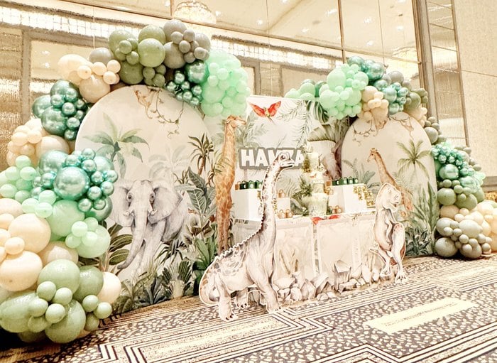 Dinosaur safari dessert display with green and neutral balloon garland