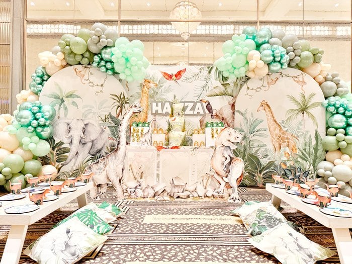 Full Jurassic safari party setup with tables balloons and animal backdrop