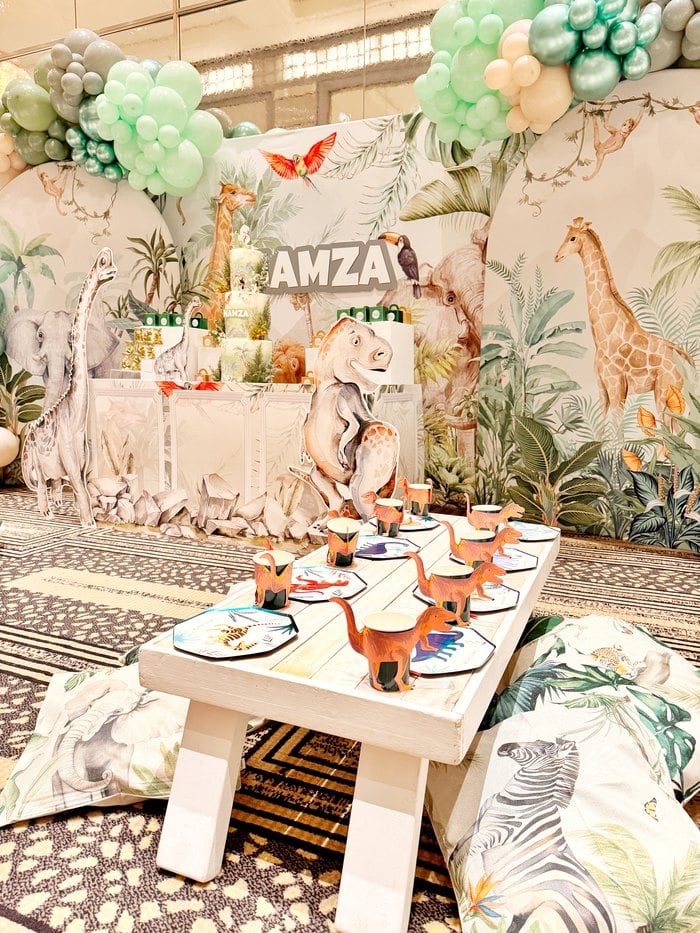 Low children’s party table with dinosaur place settings and floor cushions