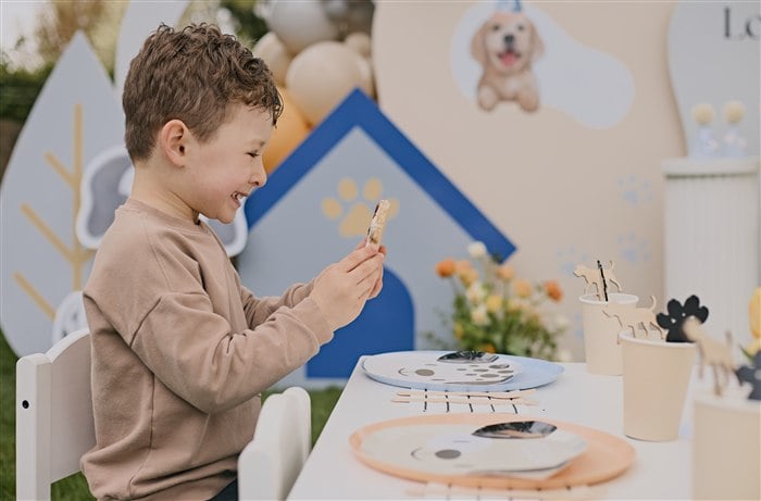 Five-year-old birthday boy enjoying his puppy party table