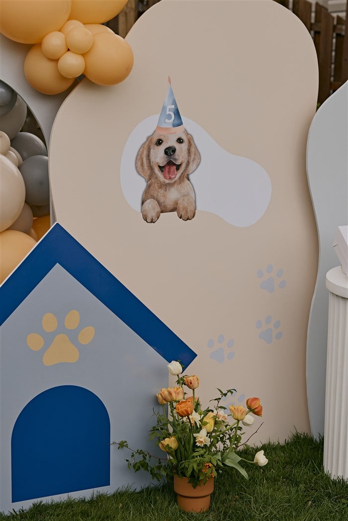 Blue dog house and puppy cutouts in the birthday backdrop