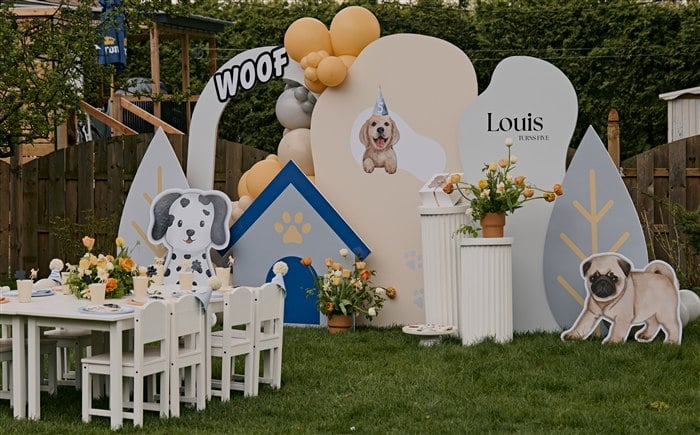 Full puppy-themed fifth birthday party setup with dog backdrops balloons flowers and a kids table