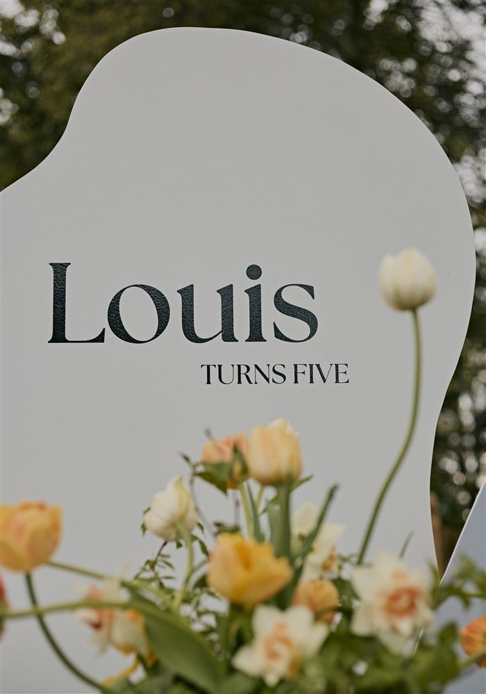 Louis turns five sign framed by orange and cream flowers