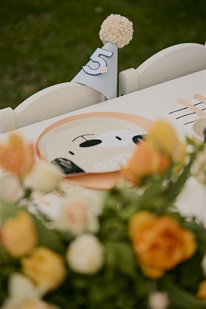 Number five party hat beside a puppy plate and floral centerpiece