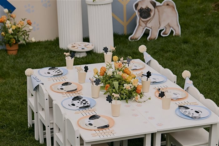 Overhead view of a puppy-themed kids table with dog plates and flowers