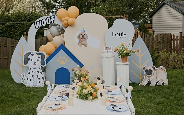Styled puppy party table with dog place settings and orange floral centerpiece