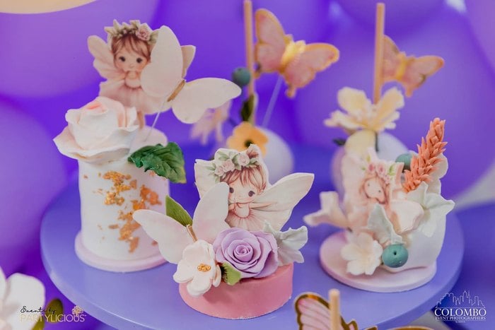 Whimsical fairy birthday cake with sculpted flowers and fairies